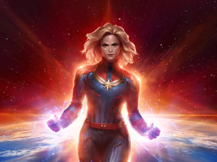 HD PC desktop wallpaper of a blonde, comic-style Captain Marvel radiating energy while standing against a fiery red-orange cosmic background.