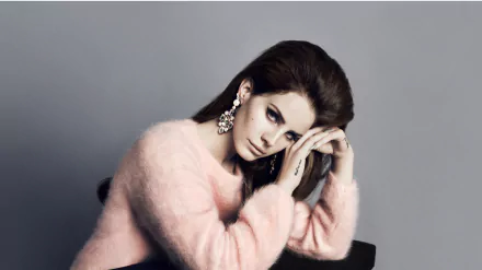 Music-themed 4K Ultra HD PC desktop wallpaper — moody studio portrait of a female singer in a pink fuzzy sweater, resting her head on folded hands against a gray backdrop.