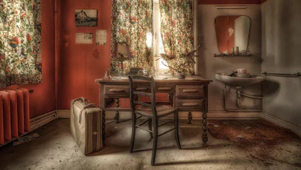 A vintage suitcase beside an old wooden desk and chair in a dimly lit room with floral curtains, captured in 4K Ultra HD for a PC desktop wallpaper.