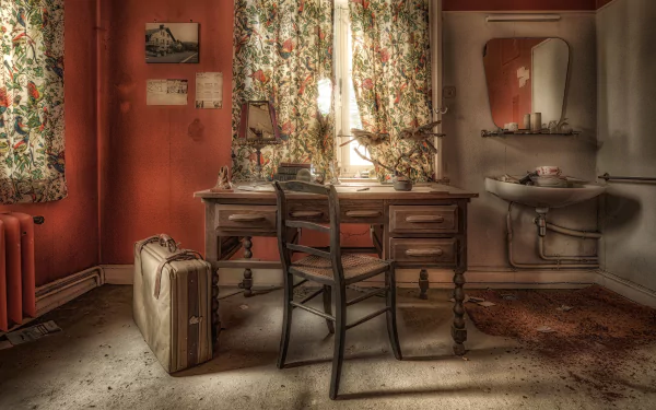 A vintage suitcase beside an old wooden desk and chair in a dimly lit room with floral curtains, captured in 4K Ultra HD for a PC desktop wallpaper.