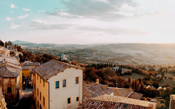 A picturesque man-made village in Italy with rustic rooftops overlooking rolling hills under a bright sky, captured in stunning 4K Ultra HD quality.