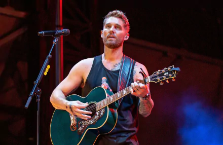 A close-up of Brett Young performing on stage with an acoustic guitar, set against vibrant lighting, creates a lively music-themed HD desktop wallpaper.
