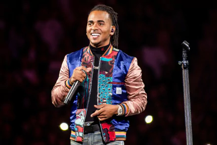 HD wallpaper of Ozuna smiling during a performance, standing with a microphone.