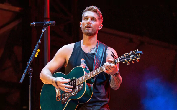 A close-up of Brett Young performing on stage with an acoustic guitar, set against vibrant lighting, creates a lively music-themed HD desktop wallpaper.
